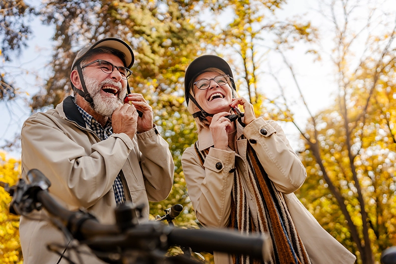 fröhliches Ehepaar zieht sich den Fahrradhelm an