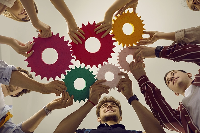 Team von jungen Menschen, die Zahnräder zusammenhalten